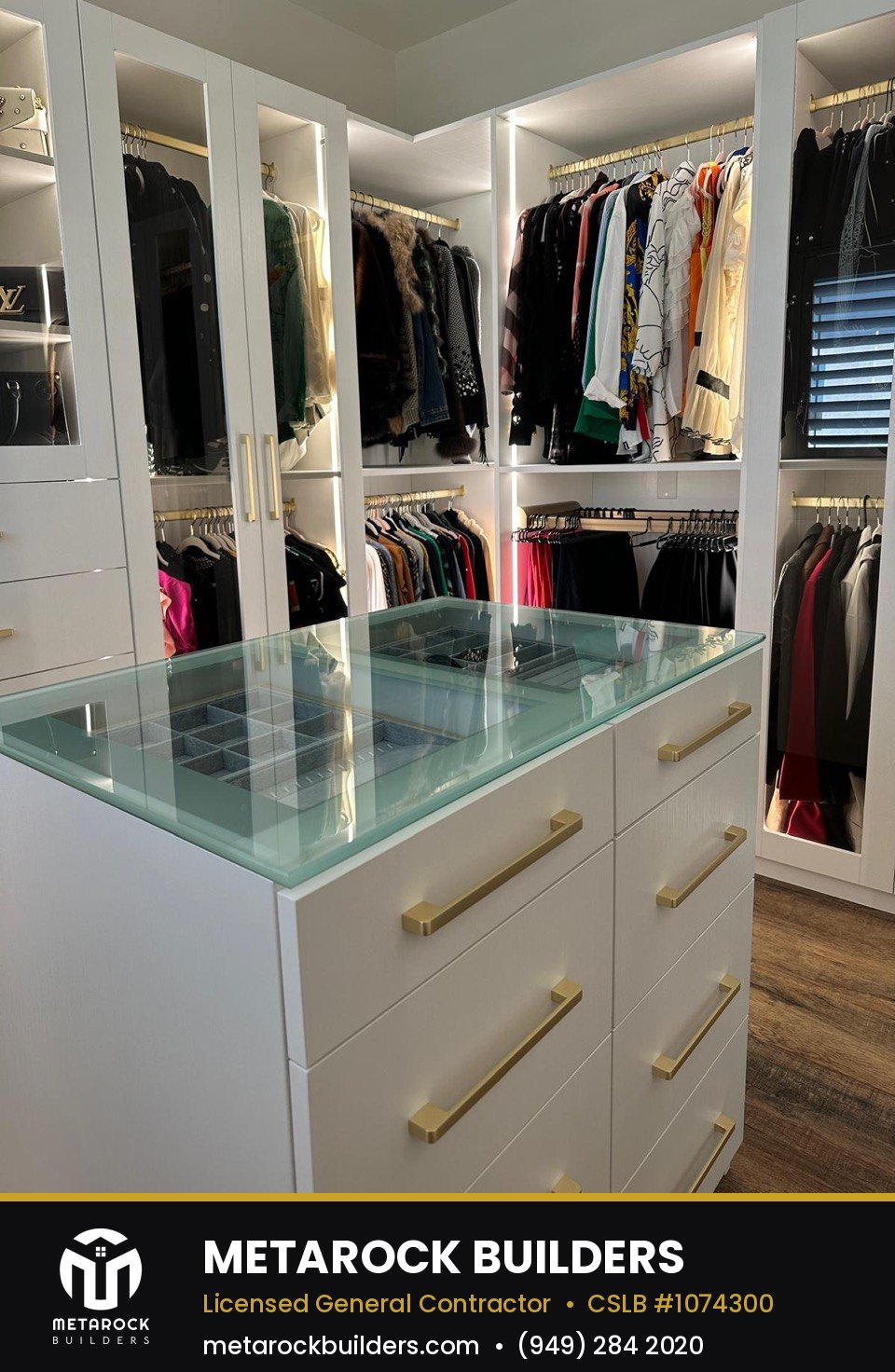 Closet remodel in Orange County by Metarock Builders, completed after photo with glass-top jewelry island and illuminated hanging sections