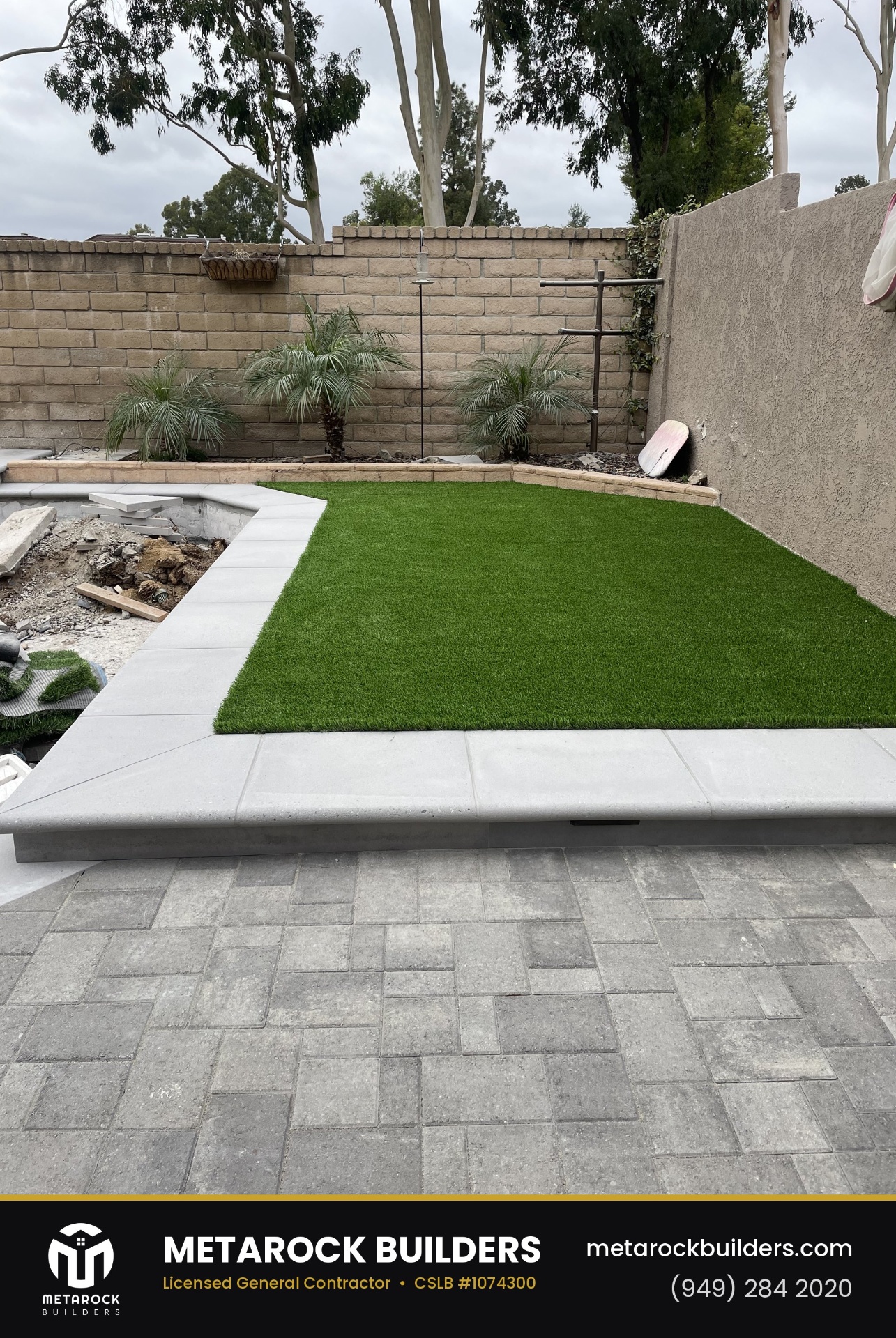 Landscaping in Orange County by Metarock Builders, completed after photo with raised artificial-turf lawn, poured concrete curb, pygmy date palms, and gray paver patio