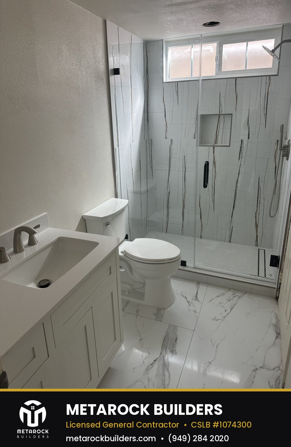Bathroom remodel in Orange County by Metarock Builders, completed after photo with marble-look tile shower, white shaker vanity, and frameless glass enclosure