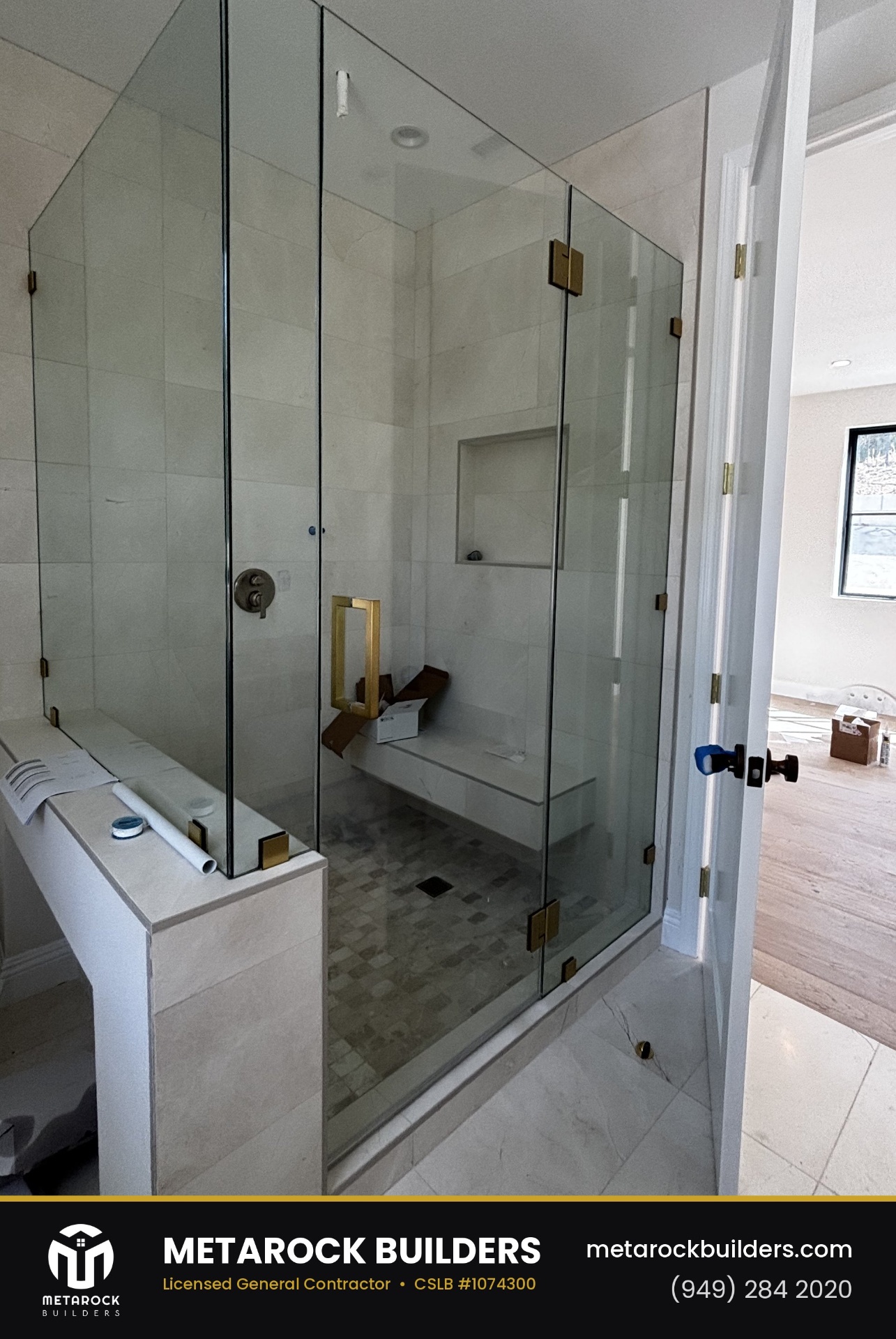 Shower remodel in Orange County by Metarock Builders, completed after photo with frameless glass enclosure, brushed brass hardware, built-in bench, and large-format stone tile