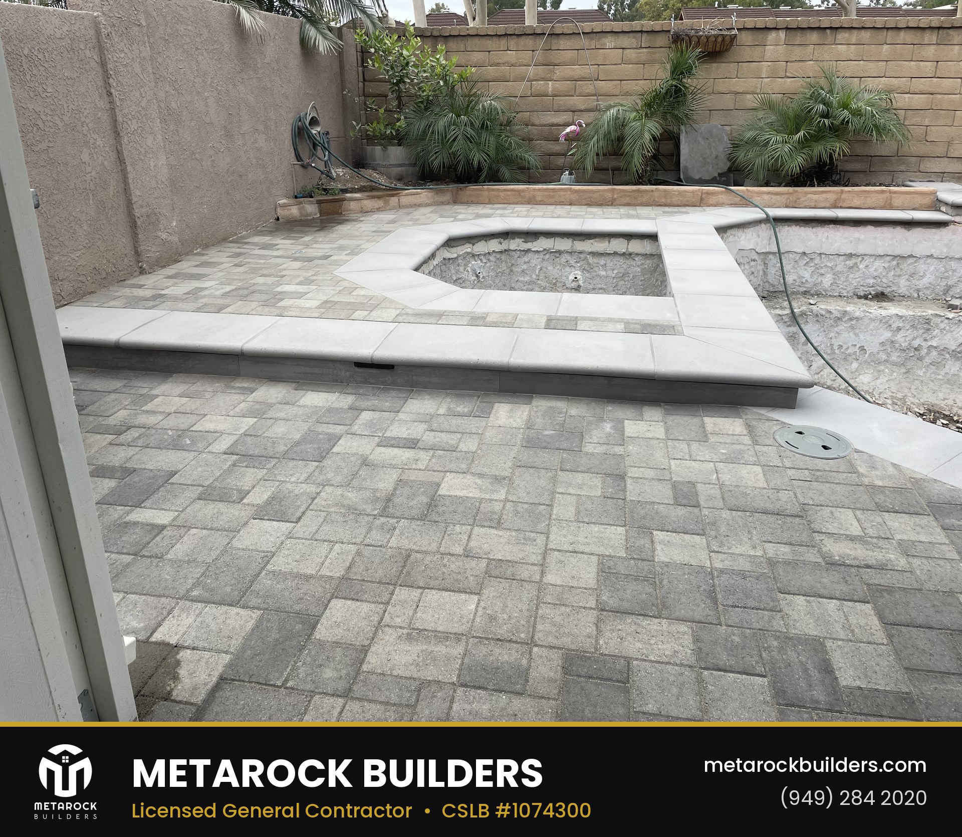 Landscaping in Orange County by Metarock Builders, completed after photo with gray paver patio, raised spa surround with poured concrete coping, and planted retaining wall