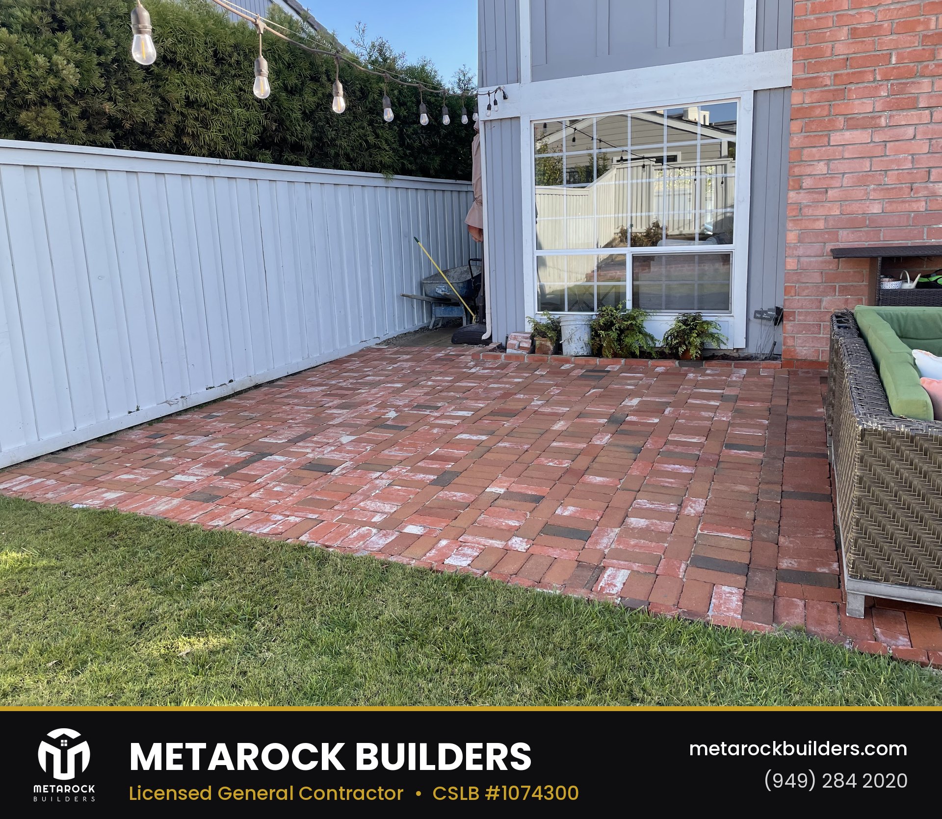Landscaping in Orange County by Metarock Builders, completed after photo with reclaimed red brick patio in basketweave pattern, string lights, and lawn border
